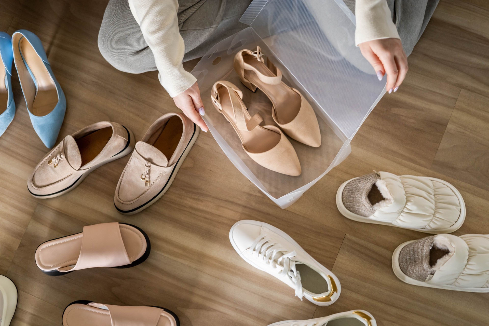 Las manos de la mujer empacan zapatos beige en tacones en una caja de plástico para un almacenamiento cómodo organizan la vista superior